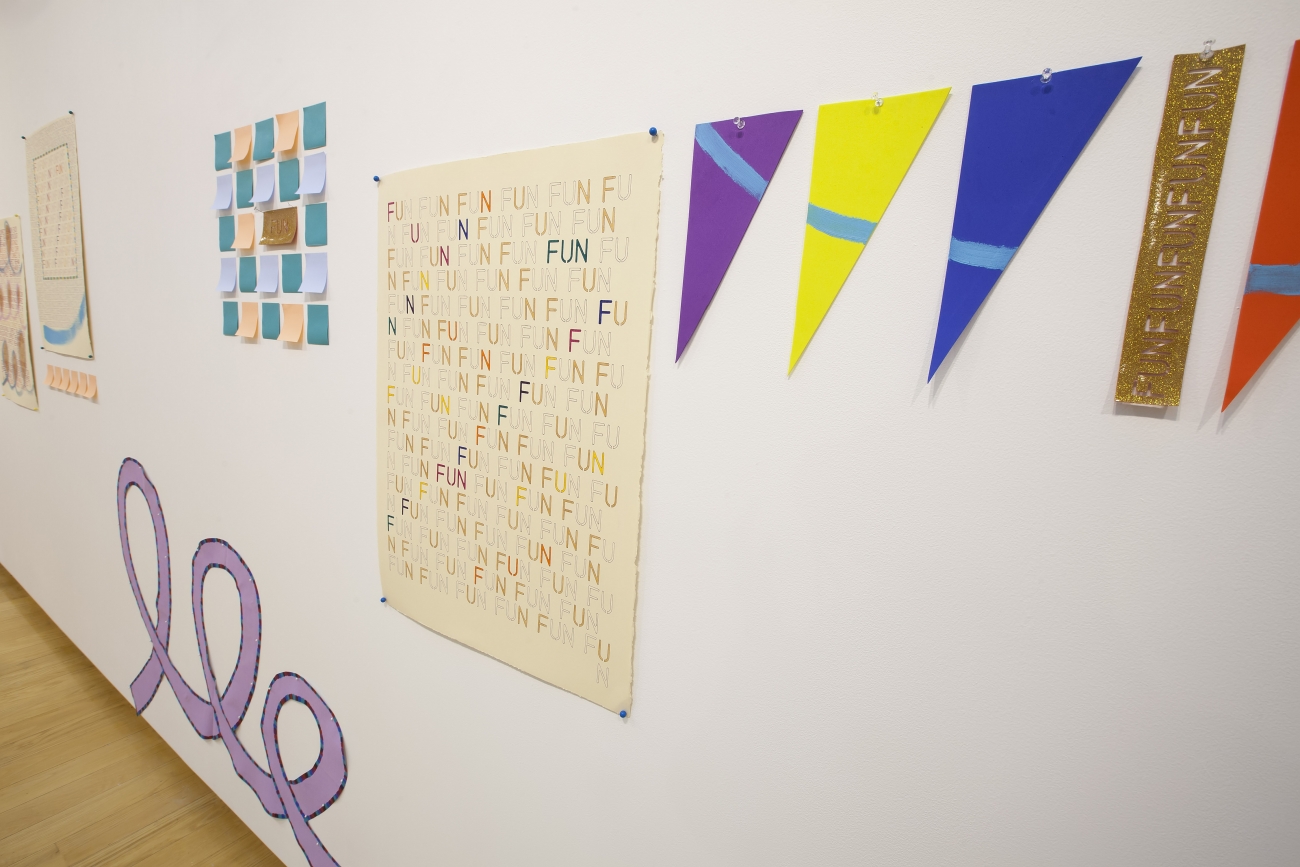 installation of prints and colored post-its on wall with purple swirl-shaped painting below