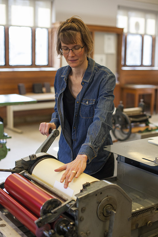 Katherine Ruffin running paper through a press in the Book Arts Lab