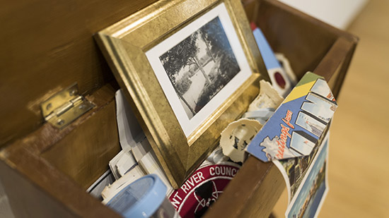 close up on gold-framed photo, post cards, and other ephemera stuffed into the top of a prayer bench