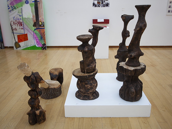arrangement of blackened and carved wood forms, some on a low pedestal, some directly on the floor