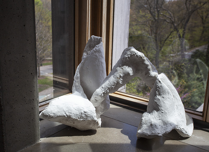 a white plaster sculpture sitting on the floor at a corner of windows