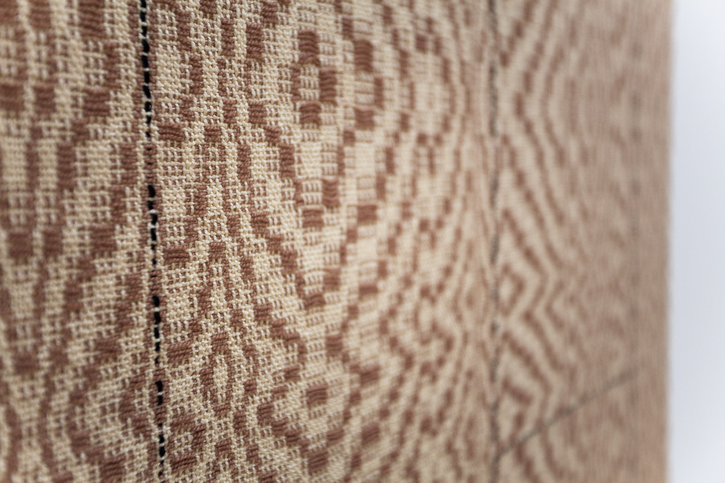 close up on a woven textile in brown and tan, the pattern mimicking wood grain