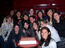 Students smiling infront of cake 