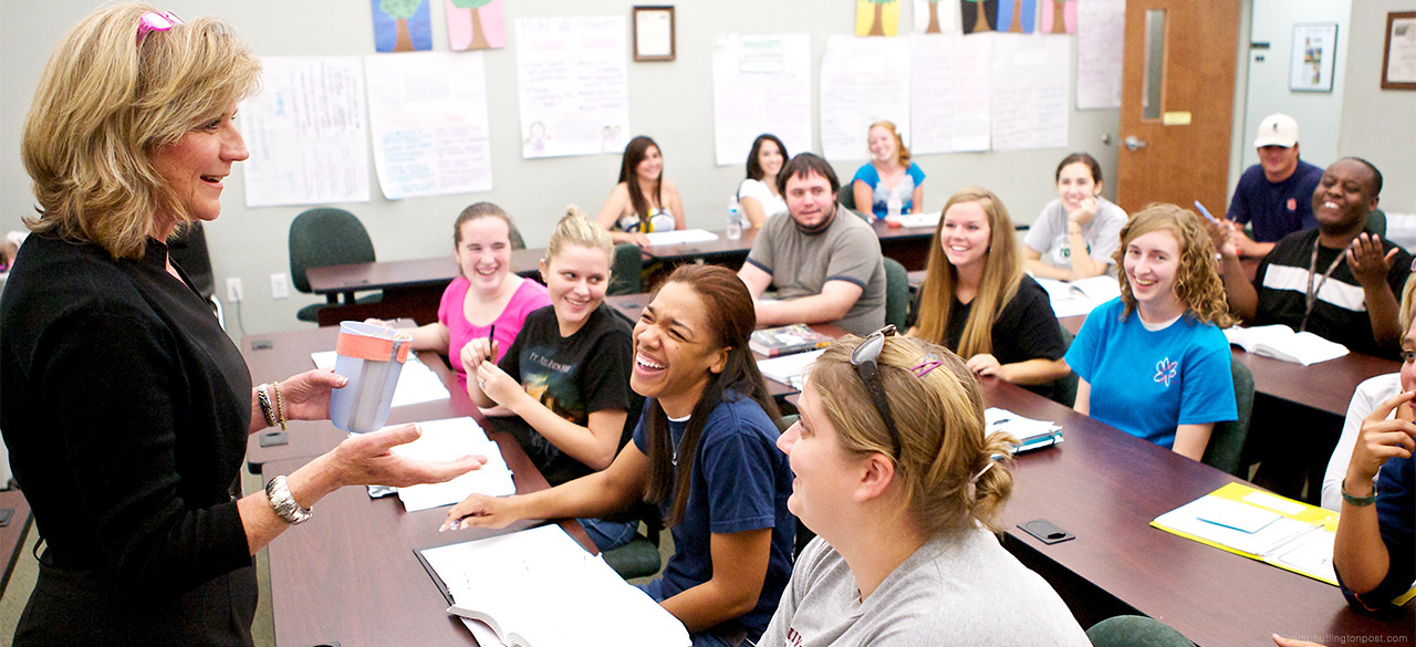 High school students engage with a teacher in a classroom. 