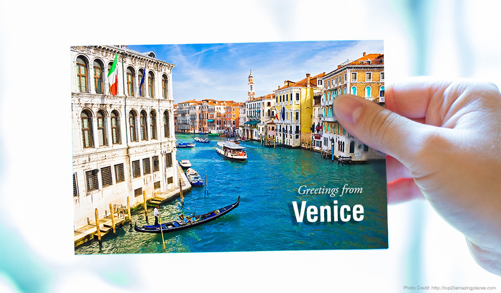 Hand holds a postcard that reads "greetings from Venice"