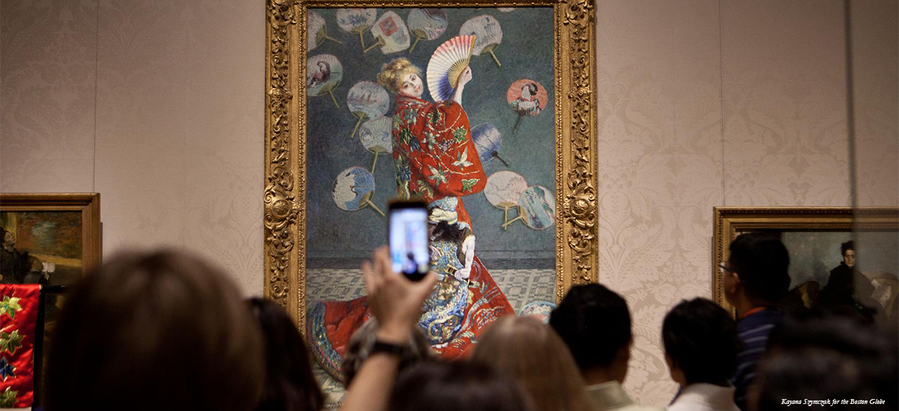 Art patron holds up a cell phone during protest MFA protest in front of Claude Monet painting