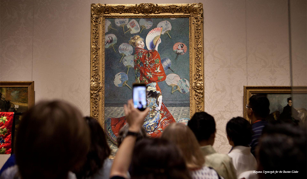 Art patron holds up a cell phone during protest MFA protest in front of Claude Monet painting