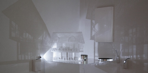 student project, a model of a house made from clear material with light shining on it with dramatic shadow