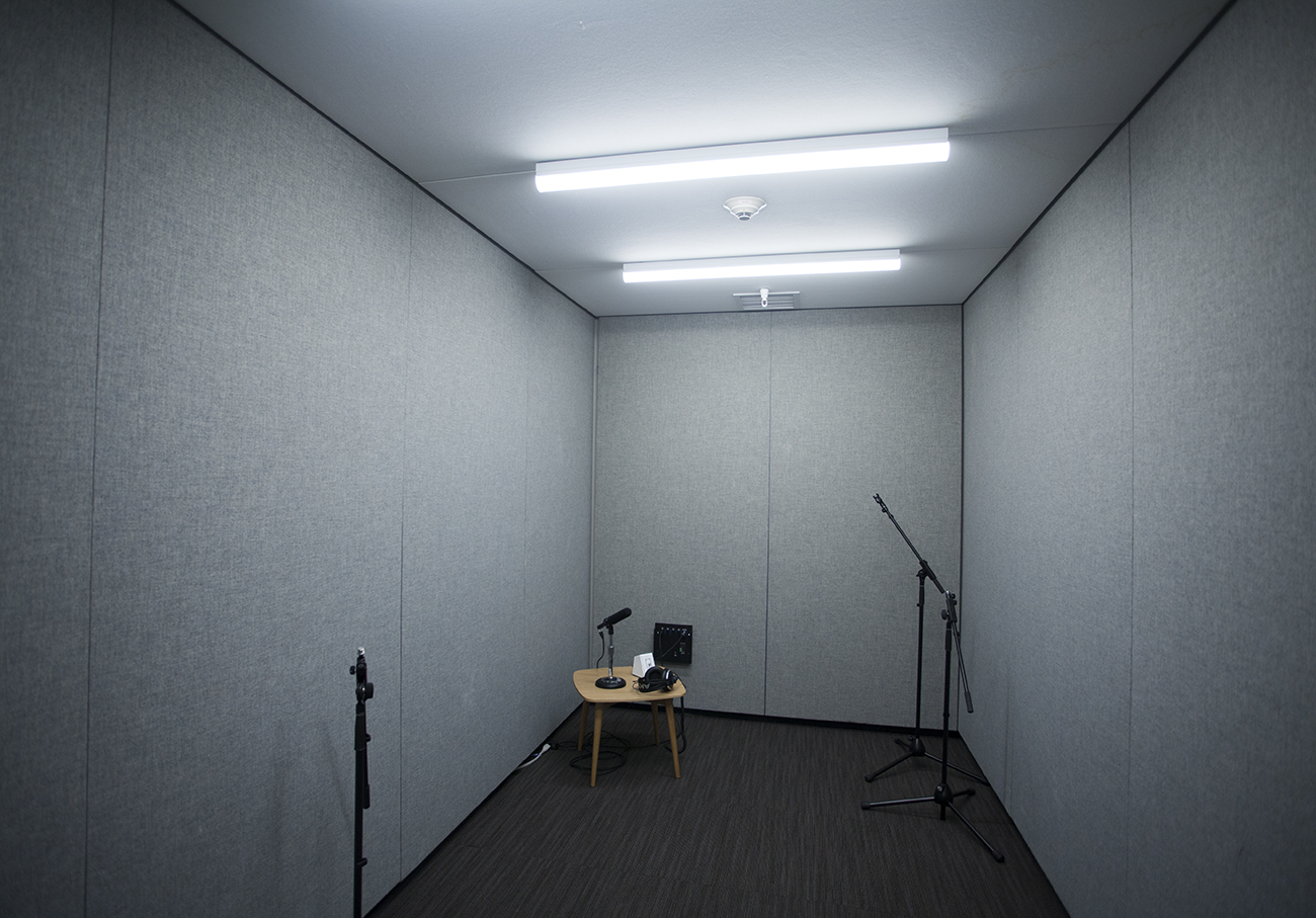 sound proofed audio recording room with gray fabric walls and microphone stands