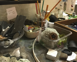 photo of various collected bits of trash in open containers in a studio