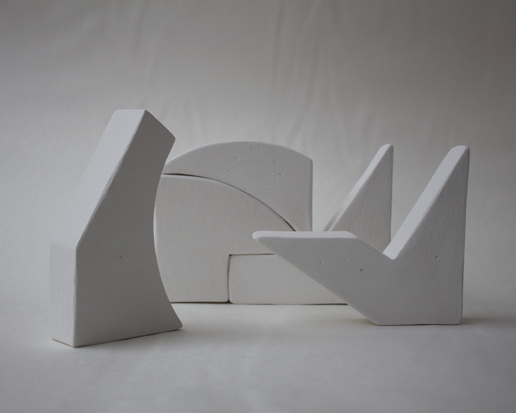 small white wooden block sculptures on white background, shadowed into shades of gray
