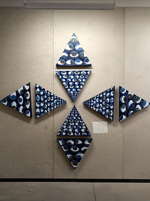 large arrangement of triangle paintings, blue backgrounds with multicolored eyes