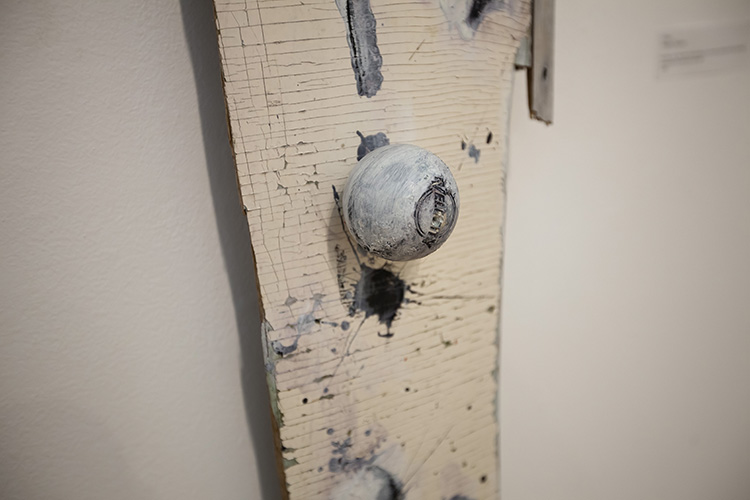 detail of a cream-painted board piece with rubber ball attached to the surface