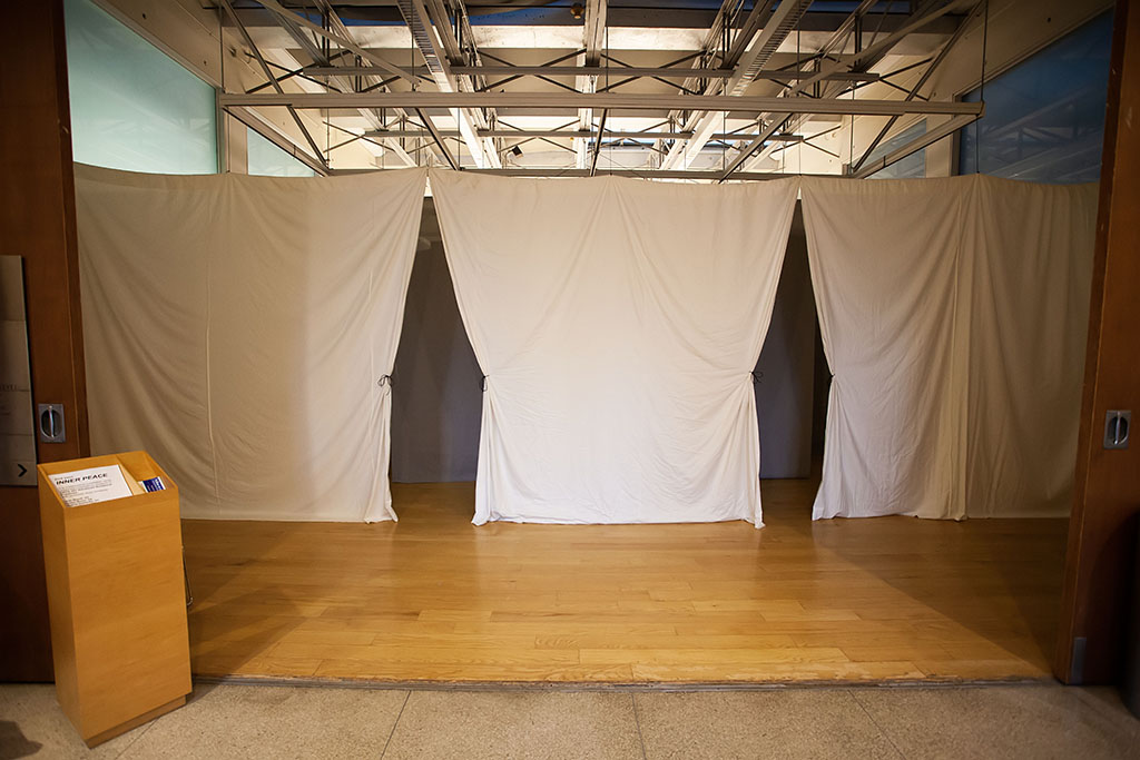 gallery entrance blocked off with hanging white fabric, parted at two points to create small tent-like entrances