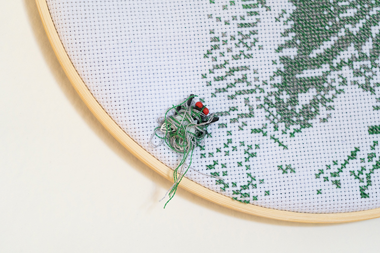 close up of plastic fly attached to embroidered design with green and silver thread