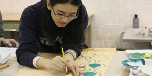 student painting blue shapes on paper
