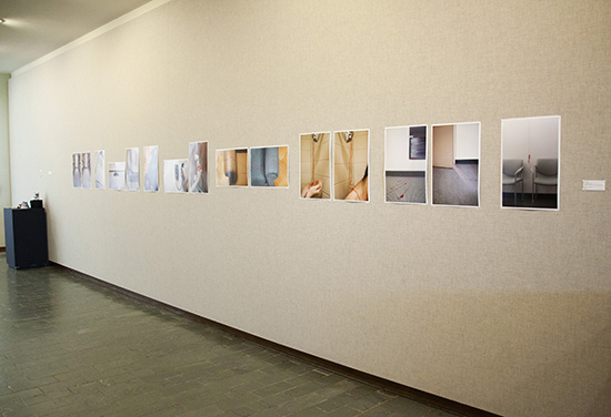 long light gray fabric wall with long series of photographs installed in a straight horizontal line across it