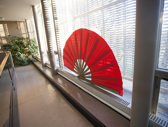 an oversized red paper fan backlit through windows on the upper level of the Sculpture Court