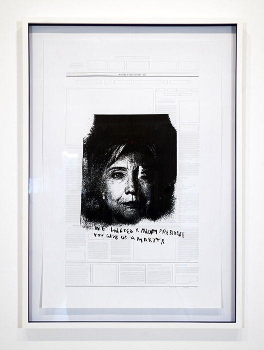 white-framed text with a dark print of Hillary Clinton over top and the roughly scrawled words 'WE WANTED A MADAM PRESIDENT/YOU GAVE US A MARTYR'