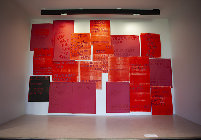 a large installation of many overlapping bright red prints with cut-out text