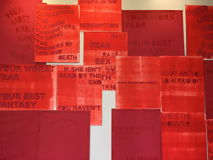 a wall covered with red prints, many with cut-out text overlays