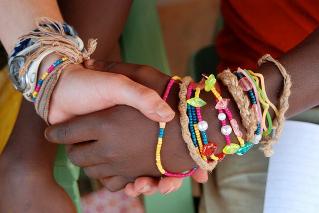 Close up of two people clasping hands wearing colorful bracelets