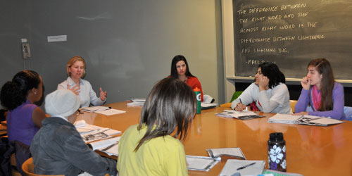 Students seated around a classroom table while the professor speaks